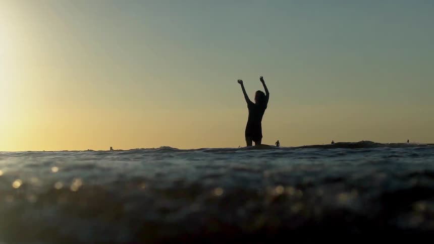 A woman stands in the tide and dances