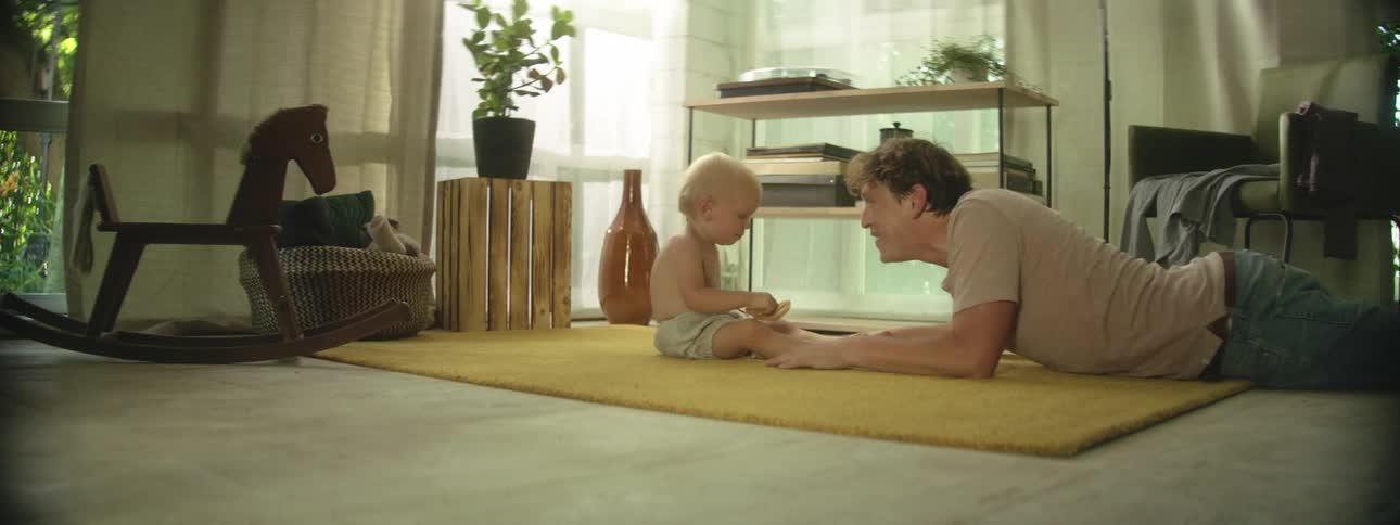 Father and baby sit on the rug and laugh in the living room