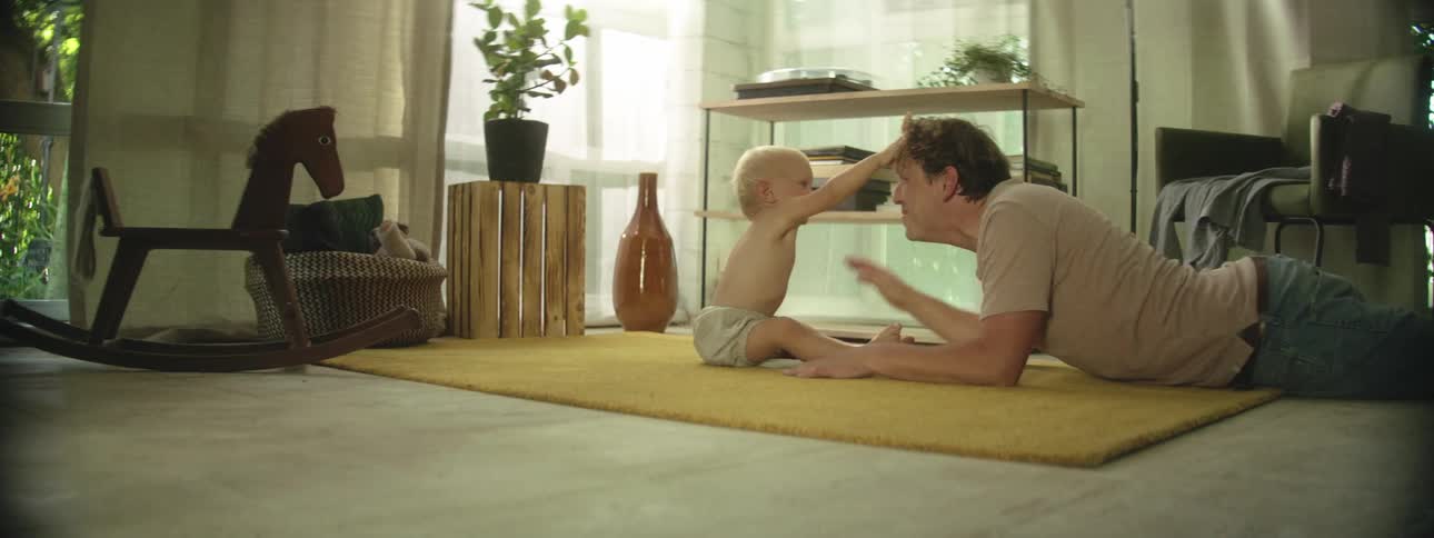 Father plays with his baby on the rug in the living room
