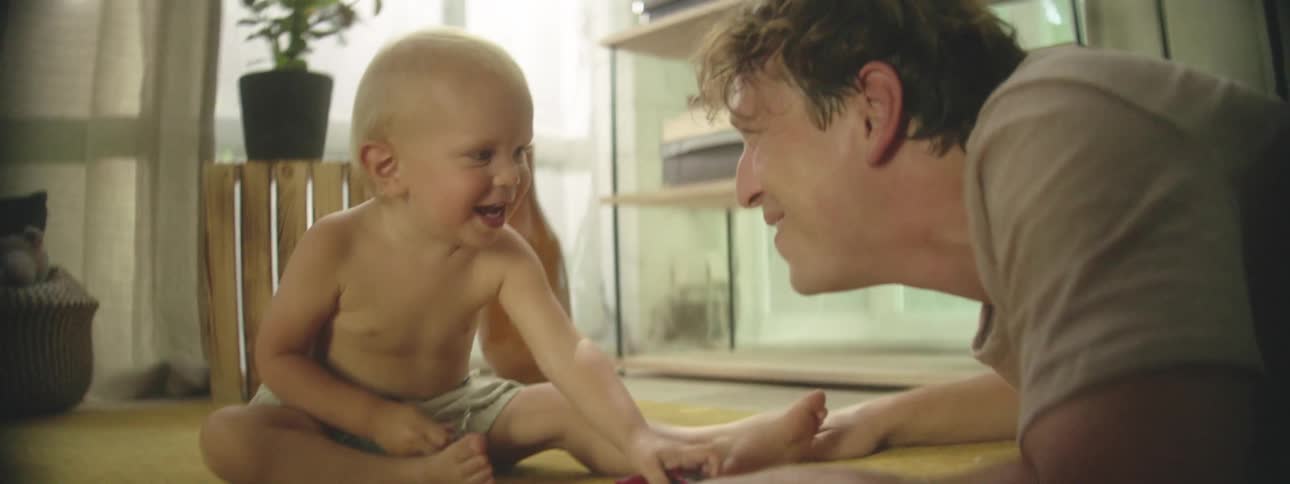 Father and son play and laugh together in the living room at home