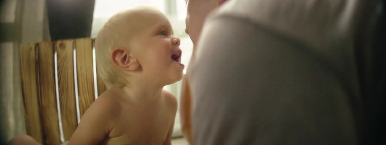 Man kisses and plays with his infant son