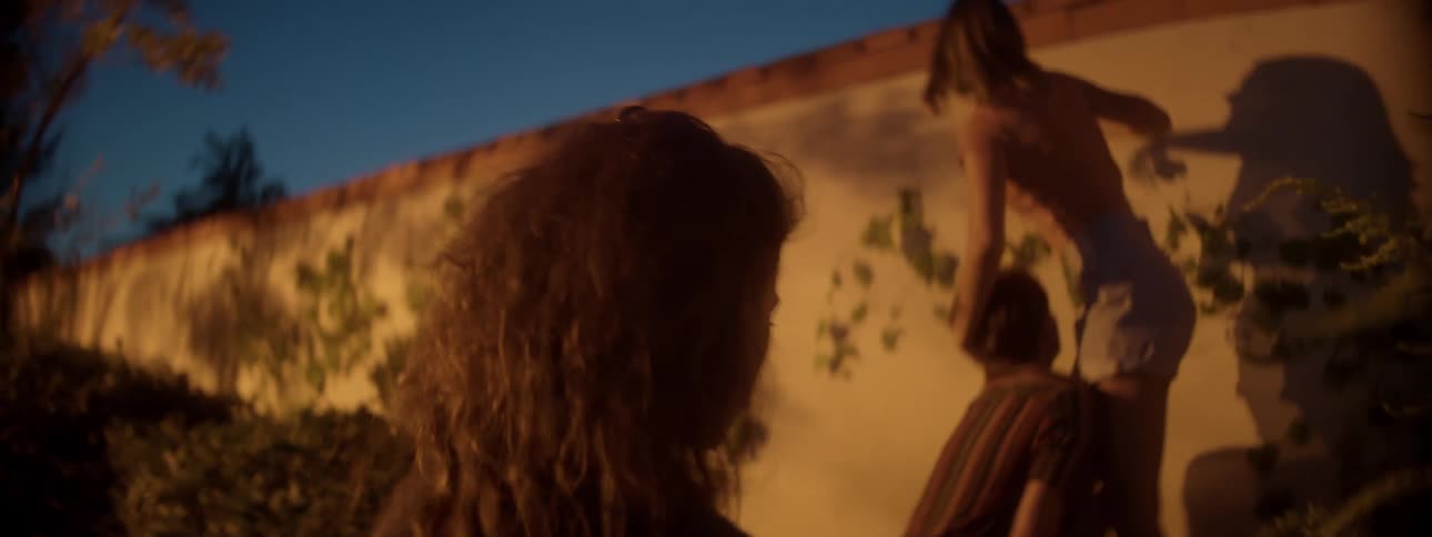 A teenager looks out for her friends as one of them tries to climb a wall