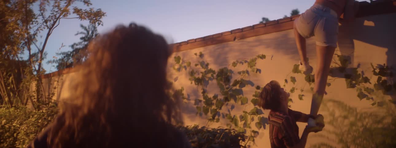 A white female teenager joins two friends attempting to climb over a wall
