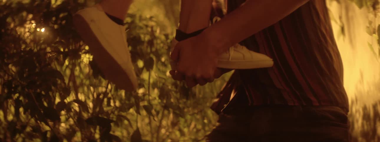 A white male lifts a white woman up while theyre outside standing by a wall