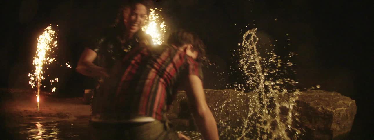 Three teens outside laugh and splash water at one another