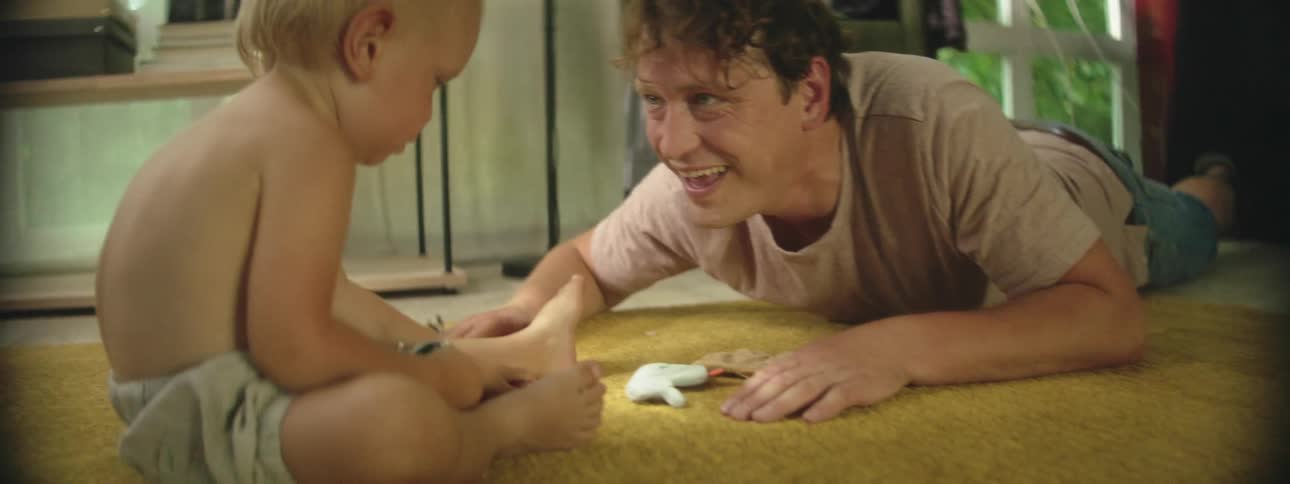 Father and son sitting on the rug enjoy themselves in the living room