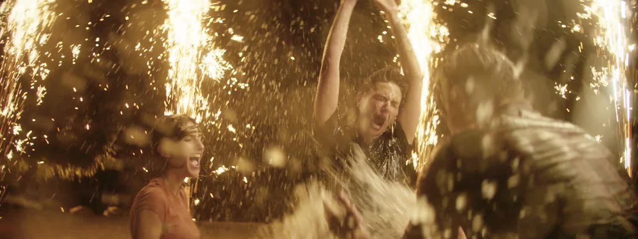 Friends play in the water surrounded by fireworks