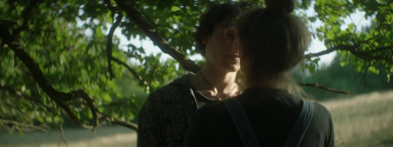 A white female teenager follows a white male teenager and touches his face