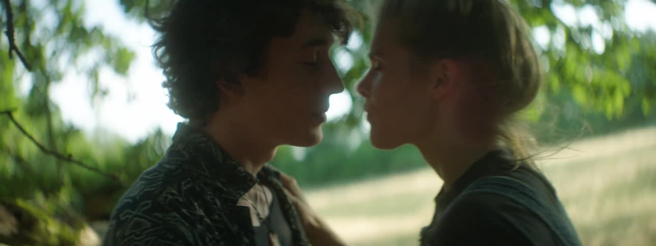 A white teenage girl gives her boyfriend a kiss outdoors