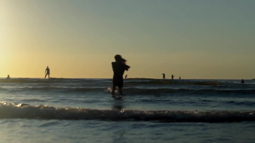 A woman dances in the tide at a beach