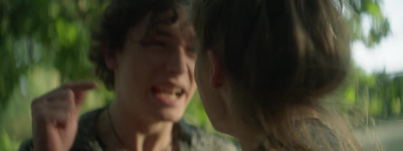 Two white teenagers argue with one another outdoors