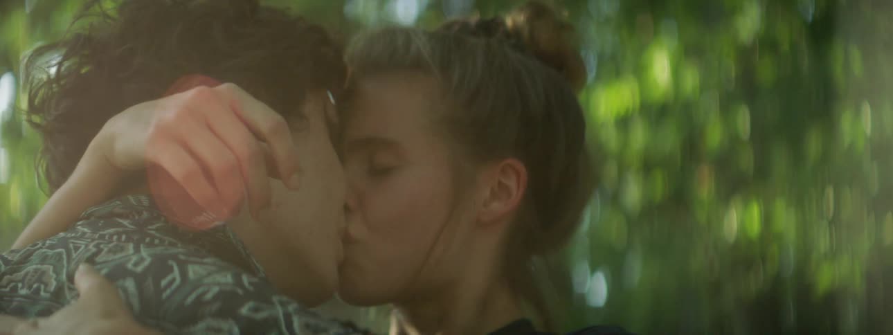 Two teenagers share a kiss outdoors