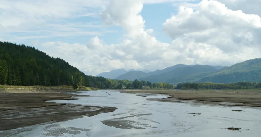 Water flows in the river next to a highway near the mountains