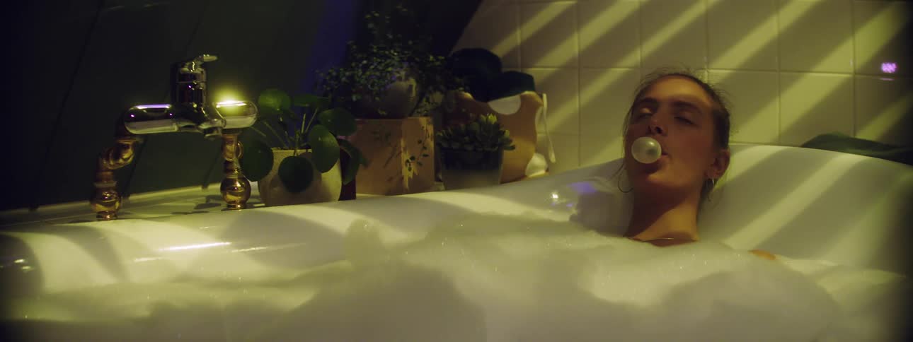 Woman chewing gum blowing bubbles while taking a bubble bath
