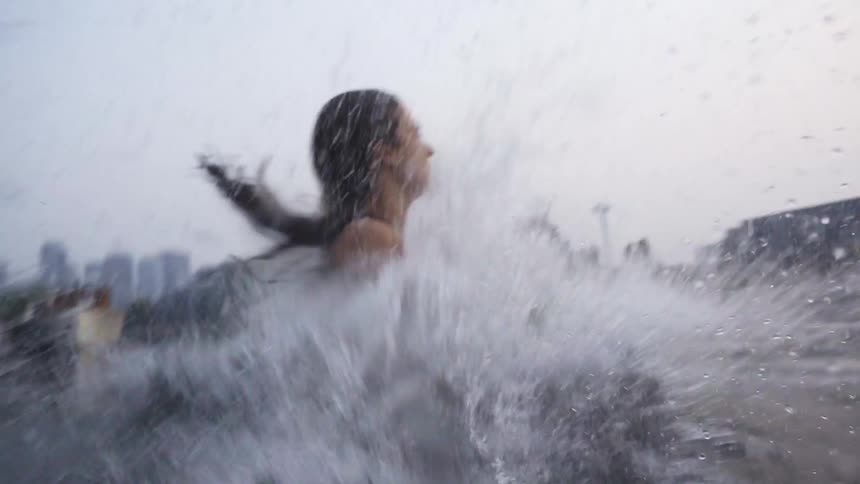 A young woman runs and jumps off a dock into the water below