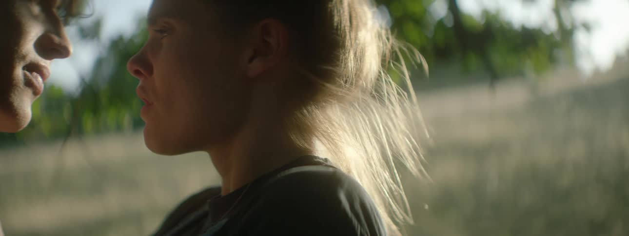 Two teens kiss each other while out in the woods