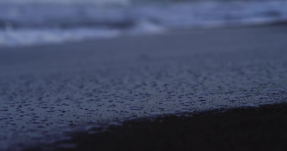 Ocean waves foam as they come to shore and then recede leaving wet sand