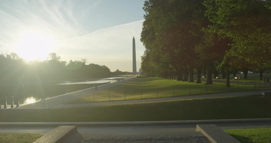 People walk and jog along a path in front of the Washington Monument