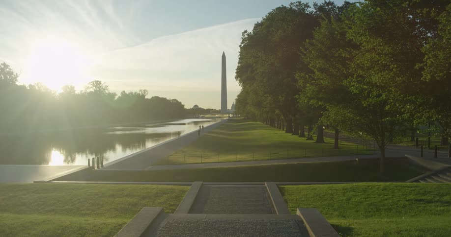 Sun reflects off of reflecting pool in Washington DC with Washington Monument in background