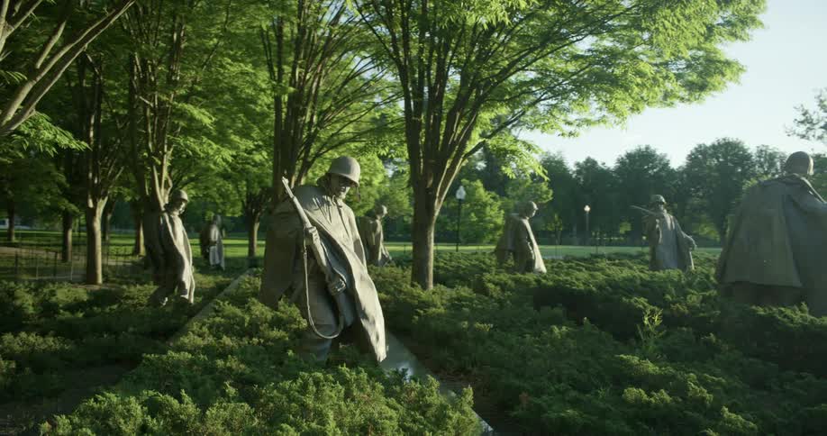 Statues of military soldiers stand in a monument in a park