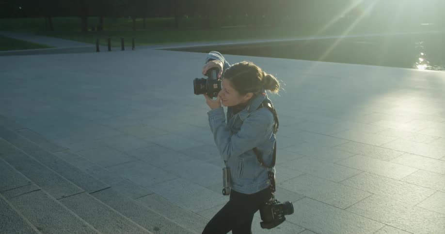 A woman takes photos on an outdoor staircase with a dslr camera