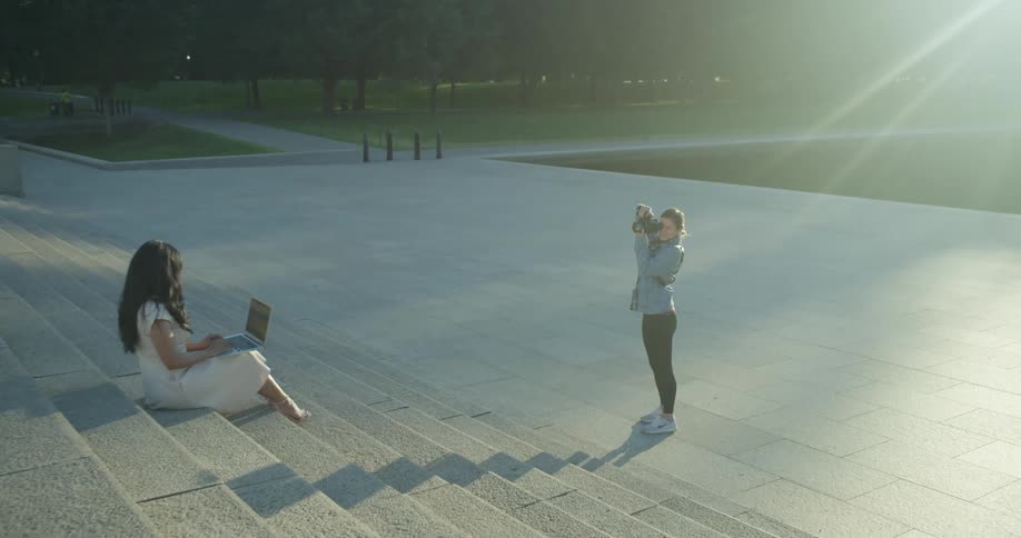 Photographer taking a picture for a photo shoot of woman sitting on stairs