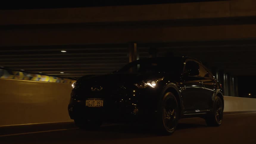 A personal vehicle drives down a road at night