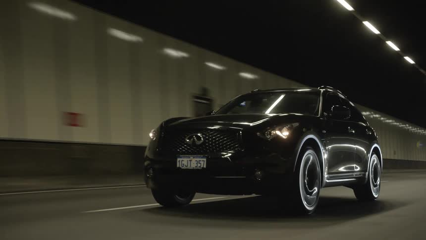 A black car traveling along a road through a long well maintained tunnel
