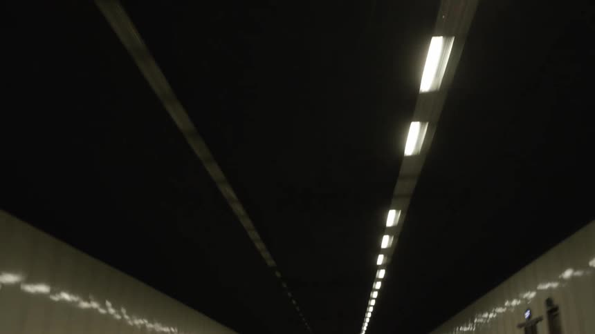 Car driving fast on the center lane in a tunnel