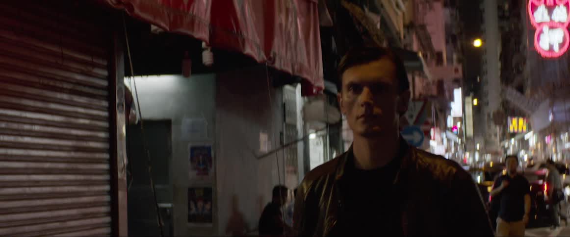 Man wearing a leather jacket walks down the street at night