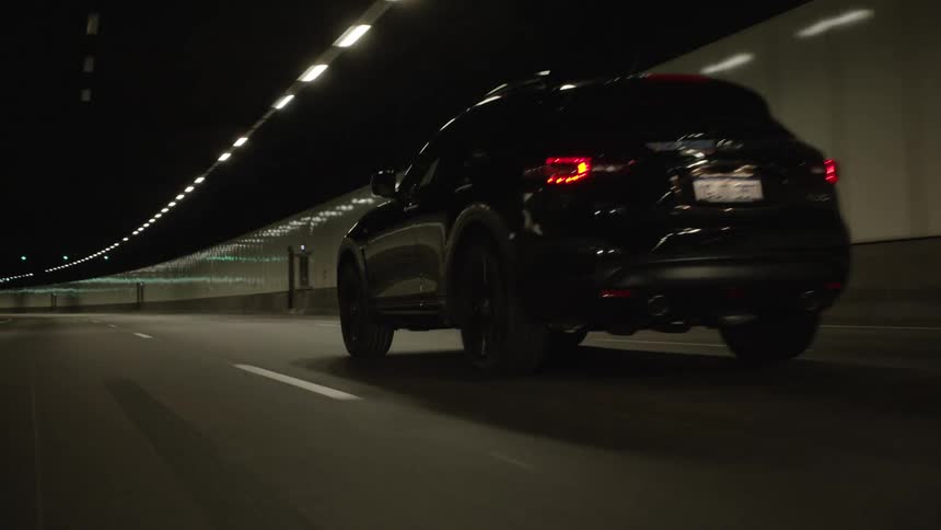 A vehicle drives down a lane of a road running through a tunnel