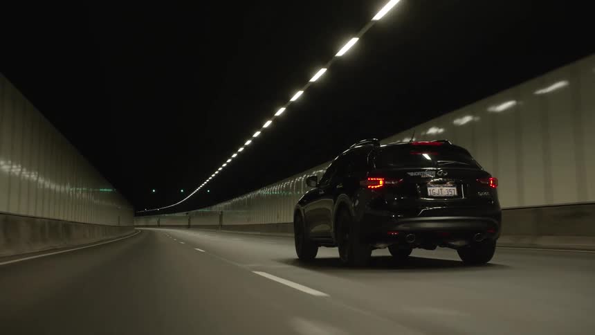 A vehicle drives on a road in a long tunnel