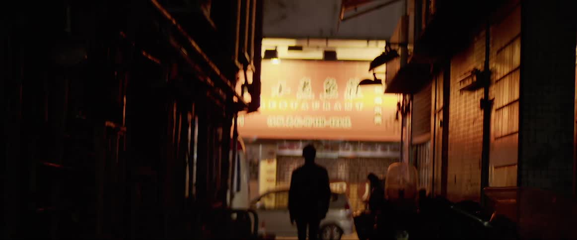 A man walks down an alleyway in an asian neighborhood in a city