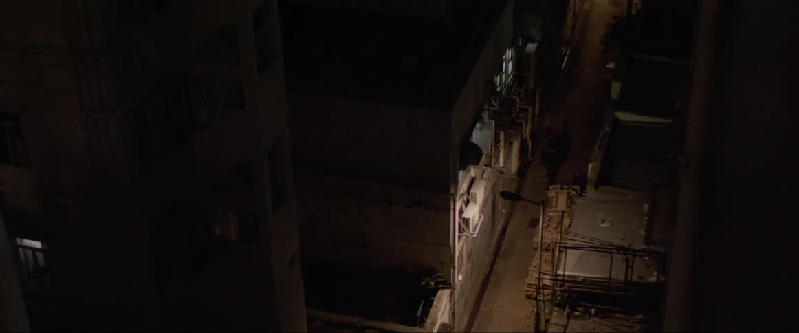 A man walks down a dark alley at night