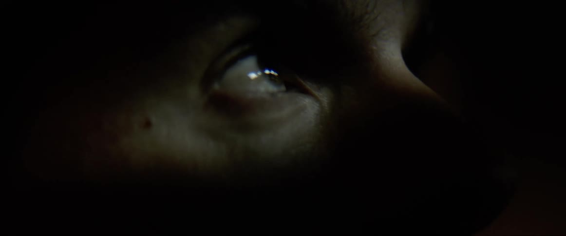 Close up of a mans eye in the darkness as he looks upwards
