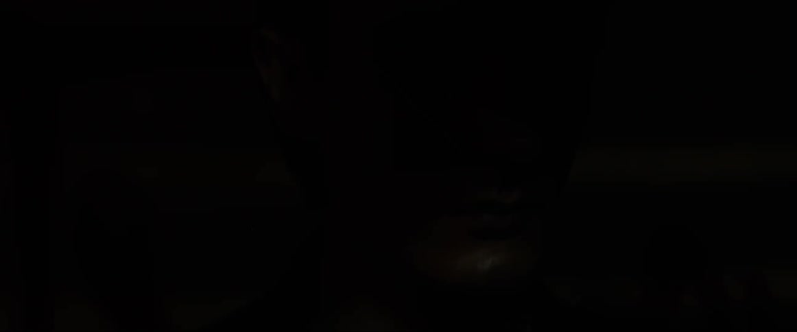 A white man with his eyes closed as a flashing light illuminates his face