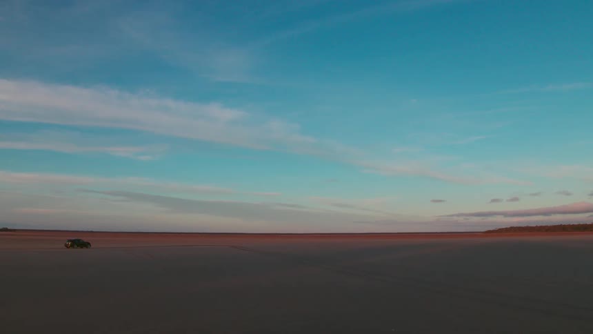 A vehicle drives across a large desert