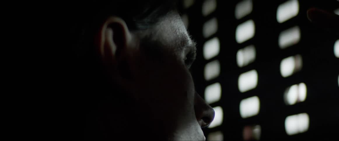 A man in some type of cage looks out through slats at the light