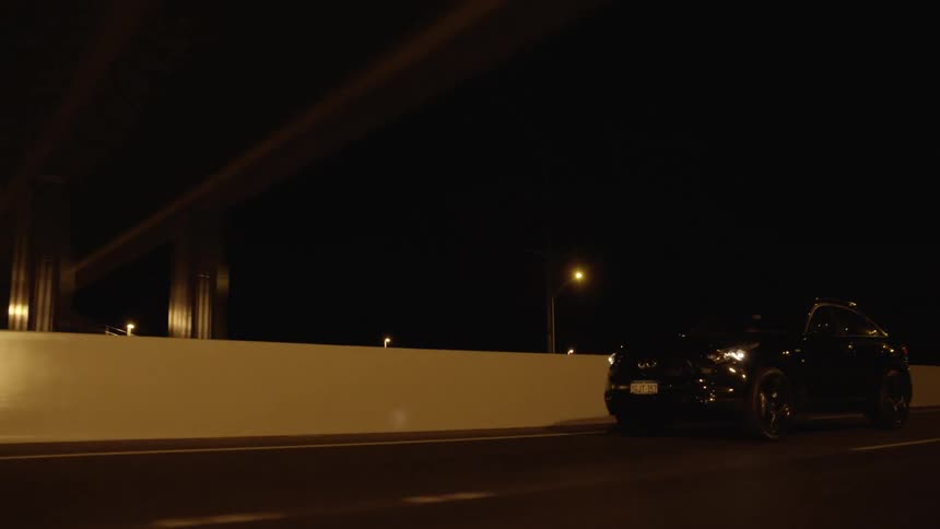 A car drives down a lane on a highway at night