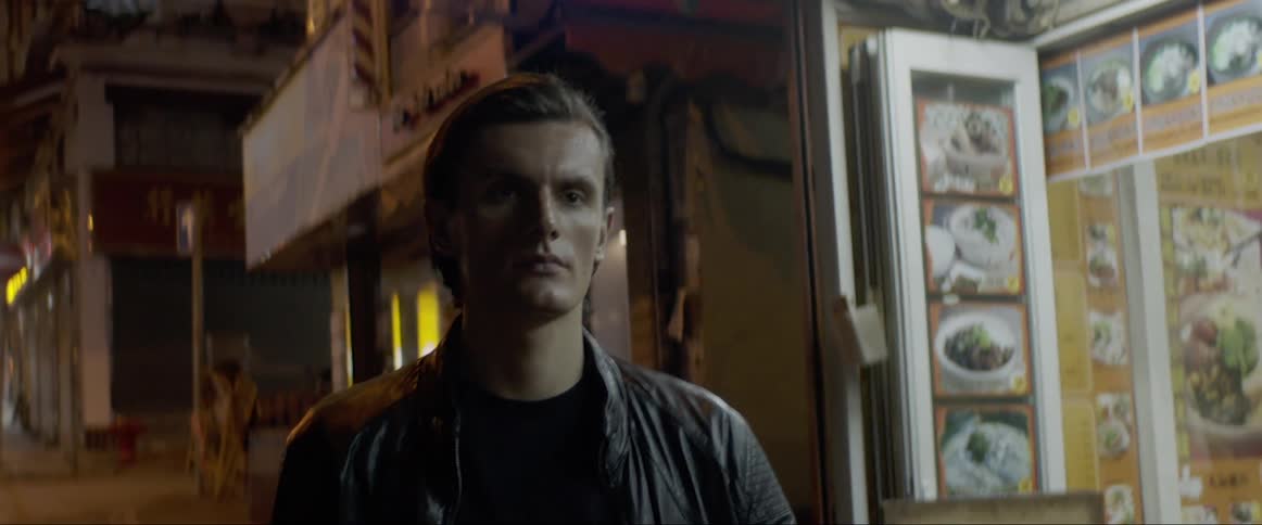 A man walks past asian restaurants and shops another turns to stare at him