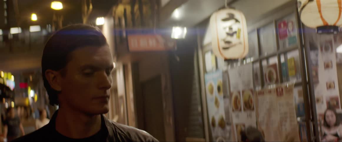 Man walks past storefront through narrow street studying menu posted in window