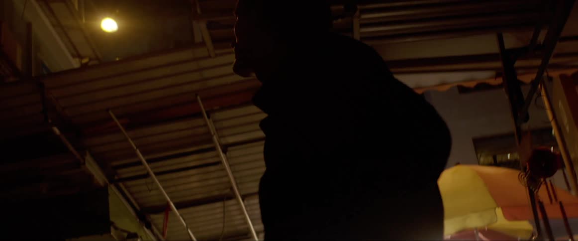 A man wanders around a city alley way appearing confused