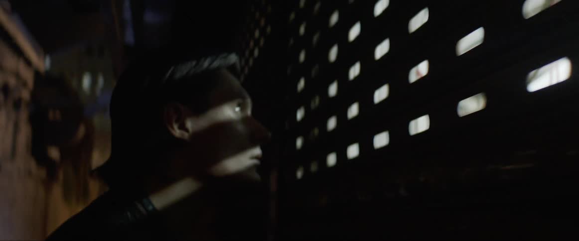 Man looking through a fence runs away on a dimly lit hallway