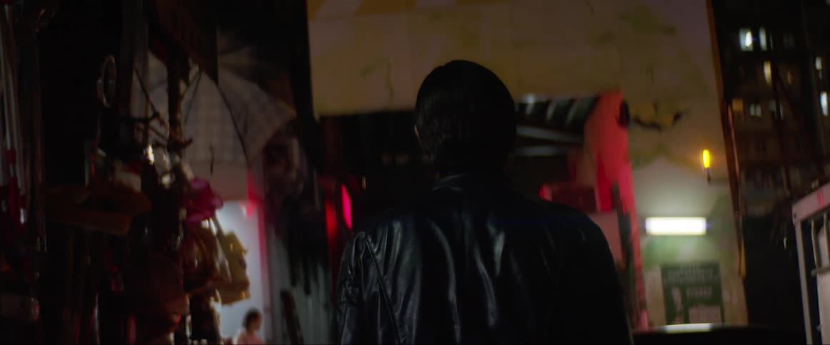 A man turns around while walking in the dark alley