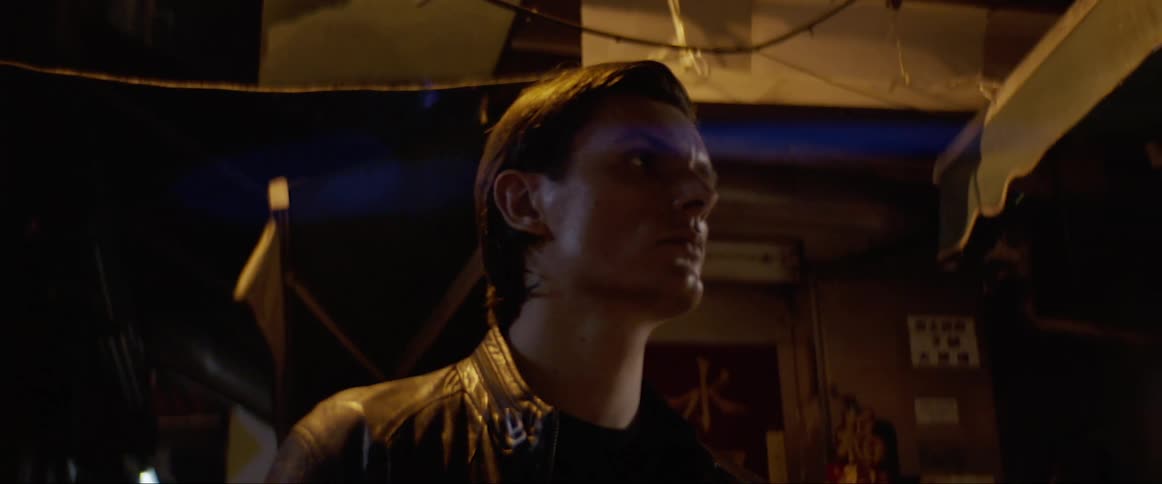 A young man stands on a quiet dark street corner and looks around