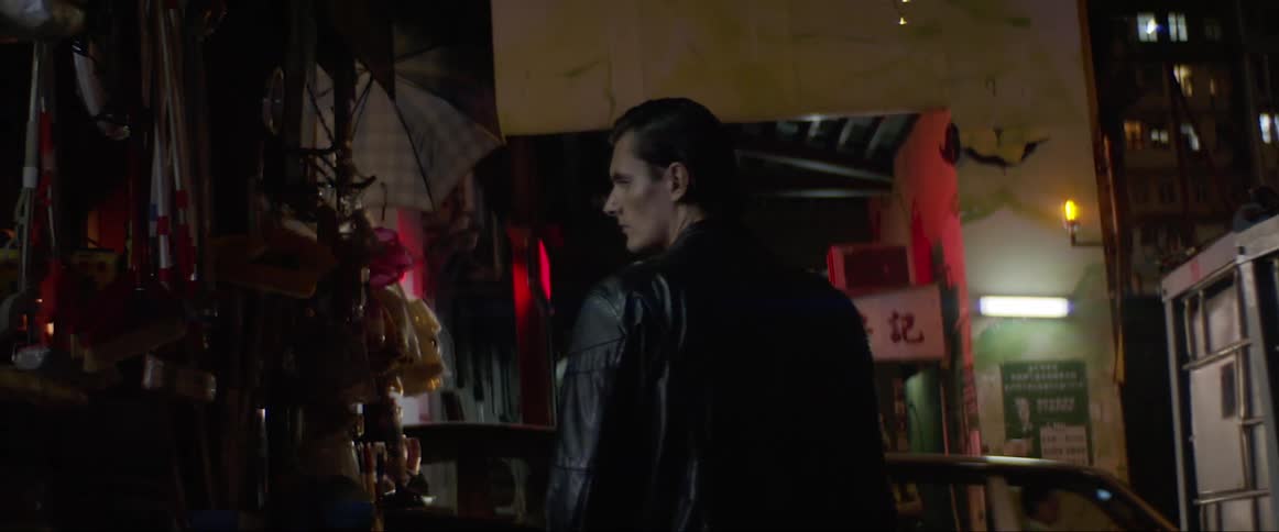 A man turns around and stops as he walks through an outdoor market at night