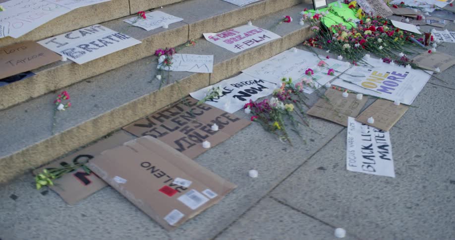 The sidewalk is covered in signs and flowers