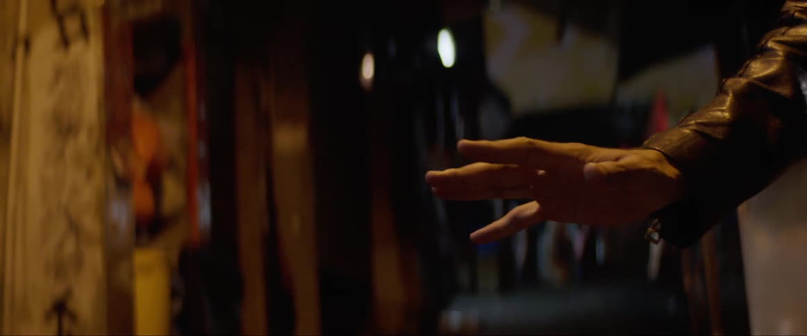 A man standing in a dark quiet street examines his hand