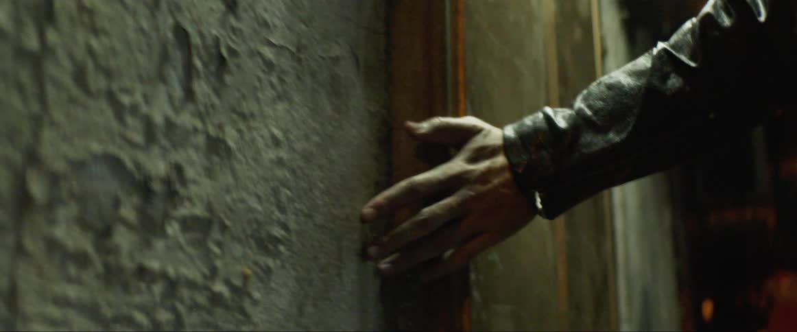 Man walks and touches on a wall in the street at night