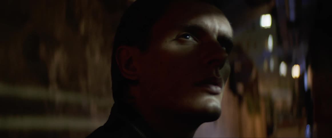 Close up of a man turning around to face the camera on a dimly lit room